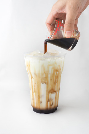 Isolated hand pouring coffee in a cup of milk (tea and syrup). Drinks menu.の写真素材