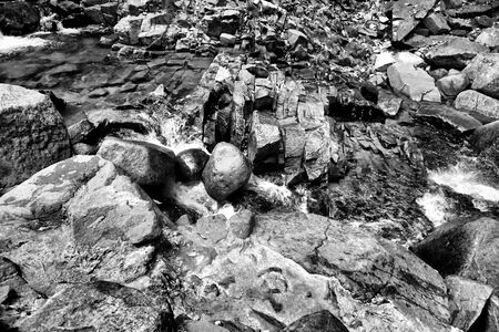 Black and white image of the stream that flows through the rocksの写真素材