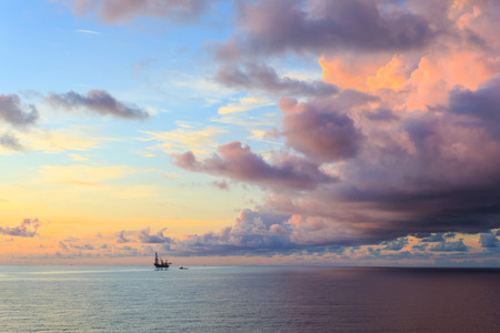 Offshore jack up drilling rig in the middle of the ocean during sunset timeの写真素材