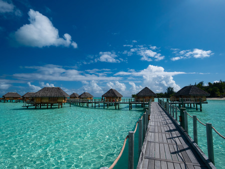 Luxury overwater villas on blue lagoon, white sandy beach and Otemanu mountain at Bora Bora island,...
