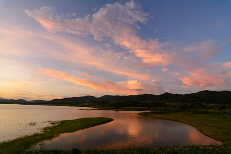 Evening Sky Reflections: Mountains, Lake, and Pink Clouds - Peaceful and Beautiful, Ideal for Background Designの写真素材