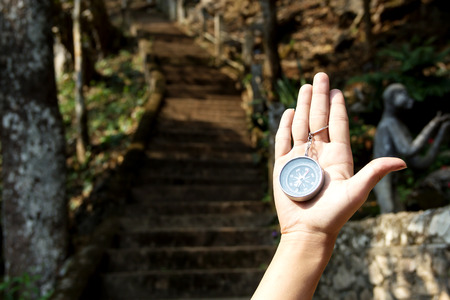 Female traveler holding a compass on nature. Point of view shot. Close-up imageの写真素材