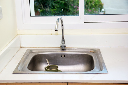 Metal faucet in a kitchen, washing ceramic glassの写真素材
