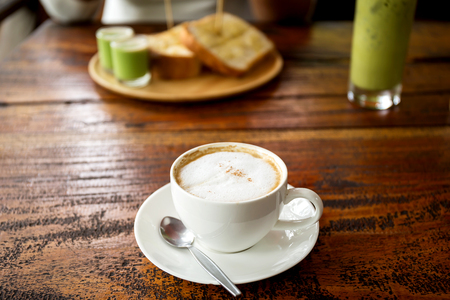 Cup of coffee with bread on wooden tableの写真素材