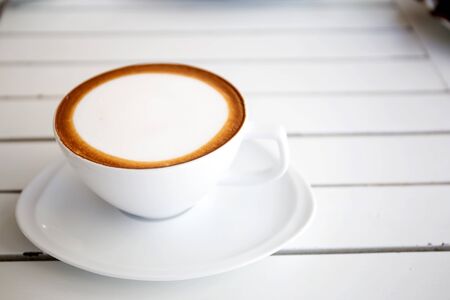 Hot coffee in a white cup on white tableの写真素材