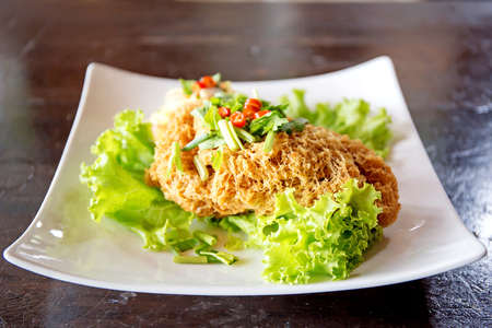 Crispy Catfish Salad Served white plate, Shredded Green Mango, Red Onion, Cabbage, Chili, Peanutの写真素材