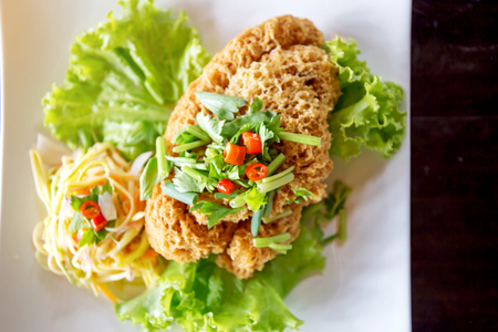 Crispy Catfish Salad Served white plate, Shredded Green Mango, Red Onion, Cabbage, Chili, Peanutの写真素材