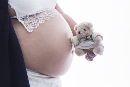 Pregnant woman with teddy bear isolated on whiteの写真素材