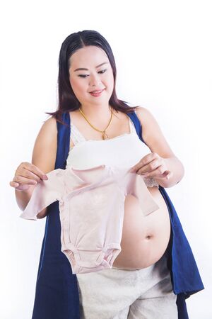 Pregnant woman showing tiny baby cloth isolated on white backgroundの写真素材