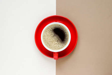 top view of hot coffee cup in red ceramic mug with red ceramic plate placed on the centre during...