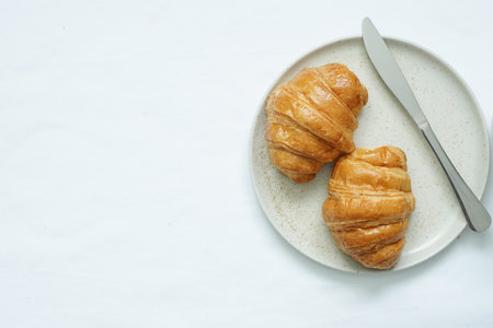 Top view of fresh croissants on circle ceramic plate placed on white backgroundの写真素材