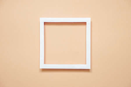top view of square white paper frame  on sand colour paper, minimal background for summer season...