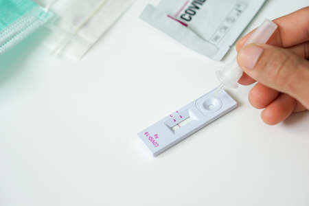COVID-19 antigen test kit self-test negative result, right hand holding a clear plastic tube...