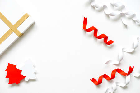 red white paper ribbon twisted,paper cut in the shape of Christmas tree with white gift box placed on a clean blank white background.Christmas and New Year background ideas with copy space,top view.の写真素材