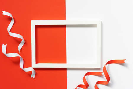 top view of white paper frame with red and white ribbons paper on white paper and red paper background.の写真素材