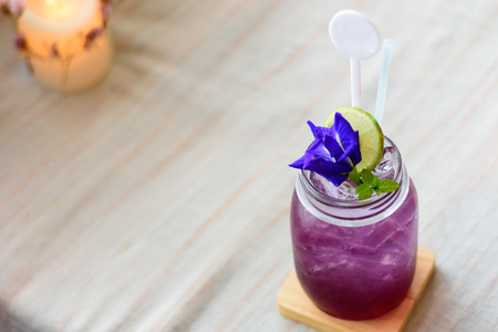 A glass of mixed juice with lemon and pea flowersの写真素材