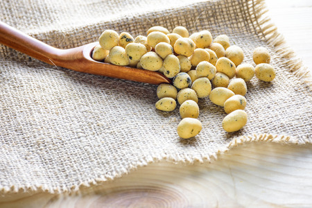 Coated peanuts seaweed flavor with wood spoon on hemp sack, wooden tableの写真素材