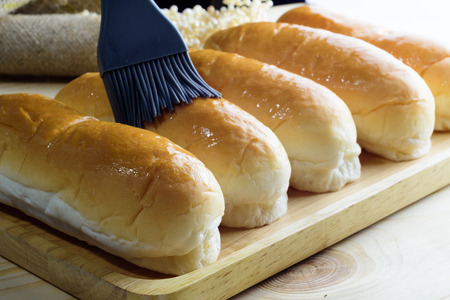 Hotdog buns in wood plate on wooden table, isolated on blackの写真素材