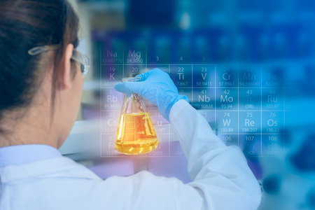 Young asian scientist with sample solution flask in hand, researching in laboratoryの写真素材