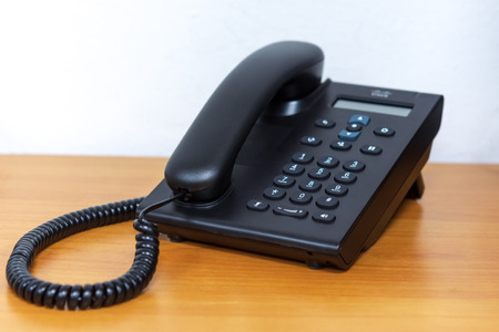 Black ip telephone device on wooden table