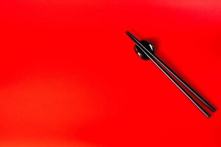 Black chopsticks with holder on red backgroundの写真素材