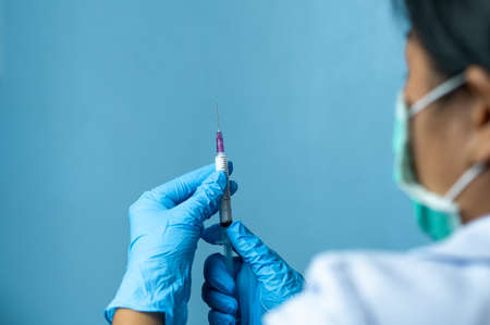 Doctor with gloves holding syringe and injectable contraceptive bottle preparing for injection