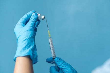 Doctor hand with gloves holding syringe and injectable contraceptive bottle preparing for injectionの写真素材