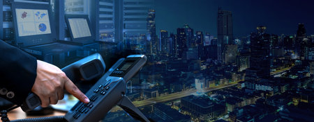 IP telephony management and telecommunications services system concept, business hand dialing ip telephone device, datacenter with rack servers and monitor, night cityscape backgroの写真素材