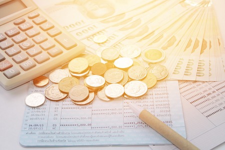 Business, finance savings or mortgage background concept ; Coins, Thai money, pen, calculator and savings account passbook on white backgroundの写真素材
