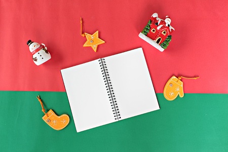Merry Christmas or Happy New Year background concept : Notebook, snowman, santa claus and christmas or new year decoration and ornament on red and green backgroundの写真素材
