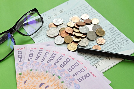 Business, finance or savings concept : Savings account passbook, Thai money baht, coins, glasses and pen on green backgroundの写真素材