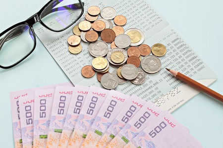 Business, finance or savings concept : Savings account passbook, Thai money baht, coins, glasses and...