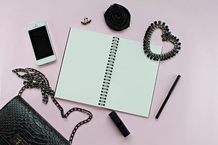 CHONBURI, THAILAND - December 5, 2016 : Top view of black woman bag with blank notebook, pen, cosmetics, accessories and Iphone5 on pink background for fashion or working woman conceptのeditorial素材