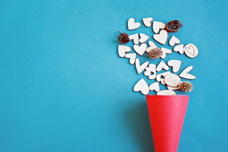 Valentines day or love concept : Wooden hearts in a red craft paper cornet on blue background