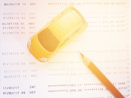 Business, finance, savings, banking or car loan concept : Miniature car model, pencil and savings account passbook or financial statement on white backgroundの写真素材