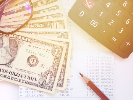 Business, finance, savings or loan concept : Money, calculator and pencil and eyeglasses on saving account passbook or financial statementの写真素材