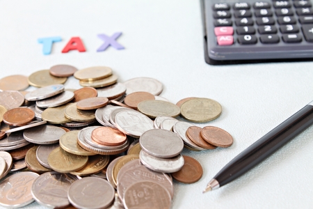 Business, finance, saving money, banking, loan, investment, taxes or accounting concept : Wooden word TAX, coins and calculator on office desk tableの写真素材