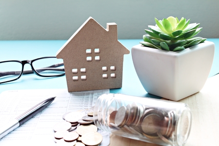 Business, finance, saving money, property ladder or mortgage loan concept : Wood house model, coins and financial statement or saving account book on desk tableの写真素材