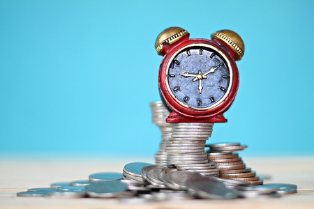 Business, finance, saving money and time concept : Miniature clock and coins stack on desk tableの写真素材