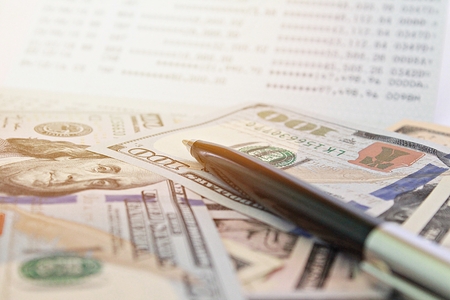 Business, finance, investment, savings or accounting concept : American Dollars cash money and savings account passbook or financial statement on tableの写真素材