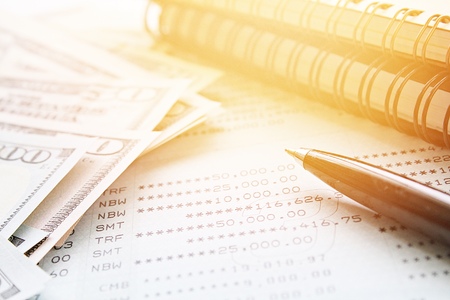 Business, finance, saving money, investment or accounting concept : American Dollar cash money, notebook paper, pen and savings account passbook or financial statement on office desk tableの写真素材