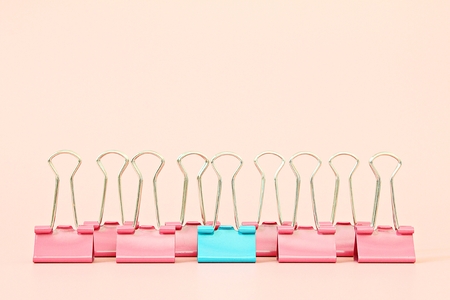 Business, office supplies, leadership, unique, individuality or think different concept : Blue binder clip standing out of pink binder clips on pink background with copy spaceの写真素材