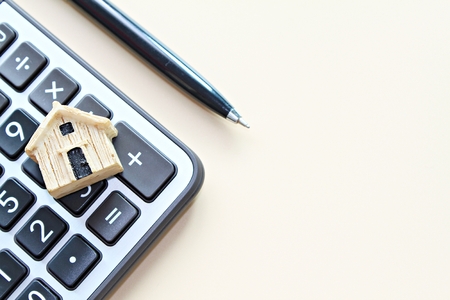 Business, finance, savings, money management, property loan or mortgage concept :  Top view or flat lay of wood house model on calculator with copy space ready for adding or mock upの写真素材