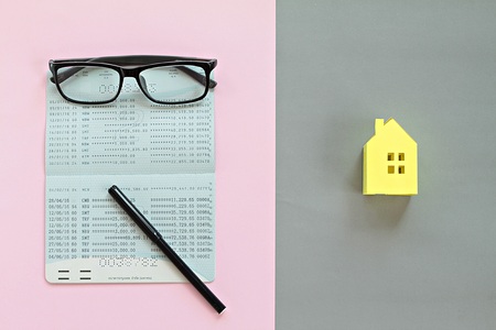 Business, finance, saving money, property ladder or mortgage concept : Top view or flat lay of savings account passbook and yellow paper house model on backgroundの写真素材