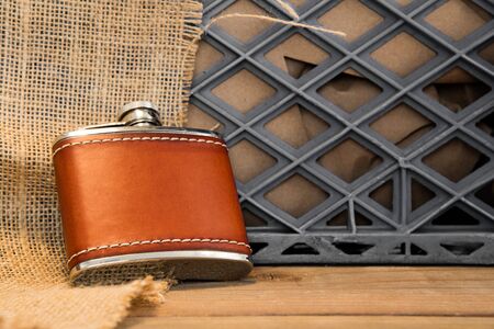 A leather covered stainless steel flask against a milkcrate and burlap.の写真素材
