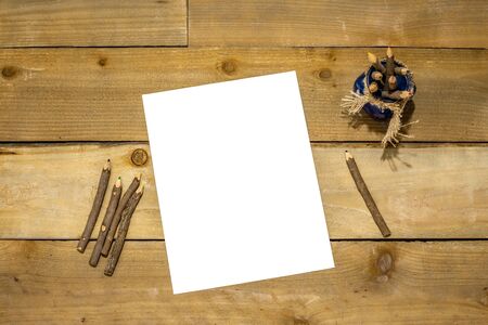 Raw wood colored pencils in a blue jar with burlap tie and white paper for your message on a rustic distressed wooden backgroundの写真素材