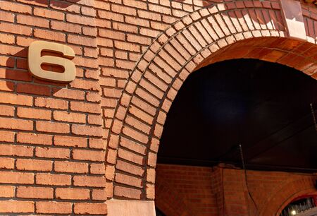 Building Number 6 in bronze sans serif font on a red brick building background. Number 6. with a long hard shadow.の写真素材