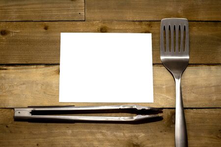 BBQ Spatula and tongs with horizontal blank 8.5x11 paper on rustic weathered wood backgroundの写真素材