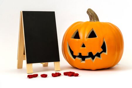 Happy plastic pumpkin with a blank chalkboard and licorice candy for office partyの写真素材