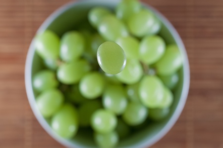 One Green Grape Falling Down to a Grape Bowlの写真素材